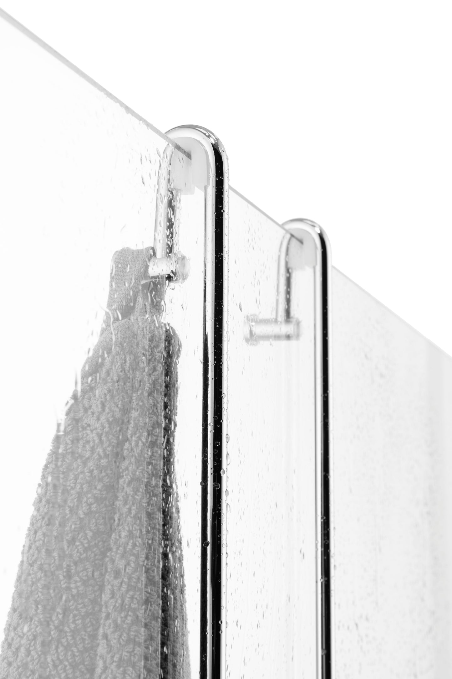 Nasse Duschglaswand im Badezimmer mit sichtbaren Wassertropfen. In der Mitte sind zwei verchromte Aufhänger eines Einhängekorbes befestigt, am linken Haken hängt ein graues Handtuch.