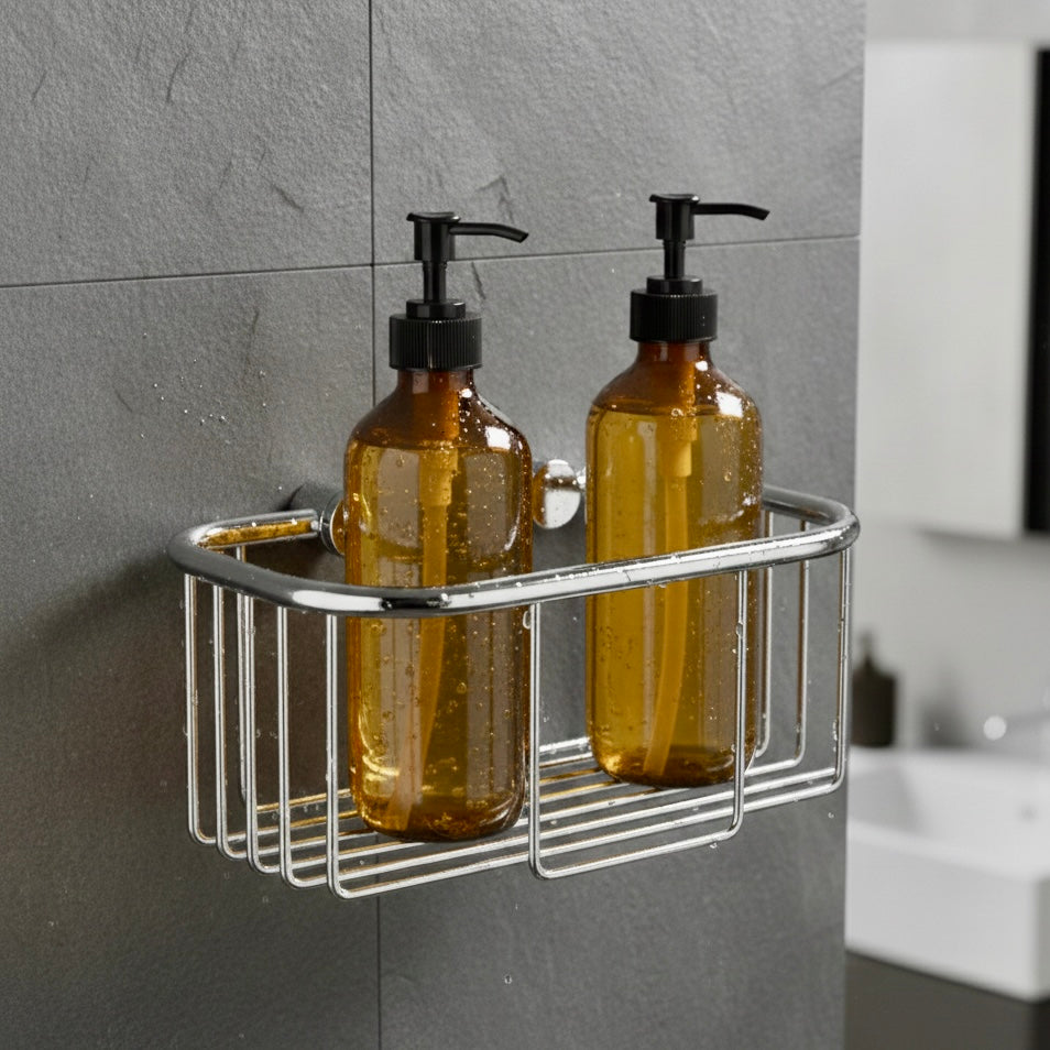 Verchromter Duschkorb zur Wandmontage mit zwei bernsteinfarbenen Seifenspendern vor einer dunkelgrauen Schieferwand im Badezimmer.