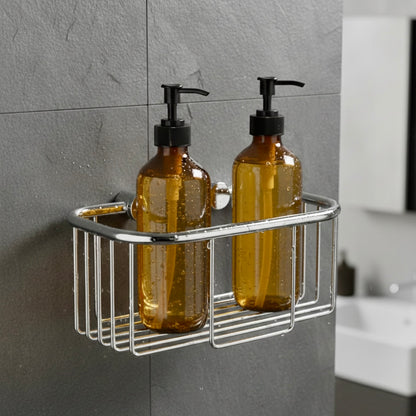 Verchromter Duschkorb zur Wandmontage mit zwei bernsteinfarbenen Seifenspendern vor einer dunkelgrauen Schieferwand im Badezimmer.